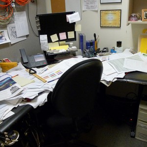 Messy freelance writer's desk in a home office.